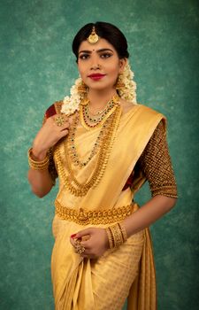 A beautiful South Asian woman in traditional attire with jewelry, posing gracefully indoors.