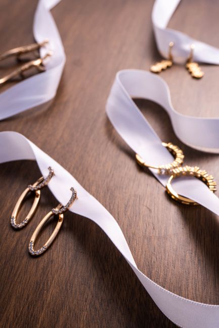 Close-up of gold earrings on white ribbon, perfect for fashion and jewelry presentations.